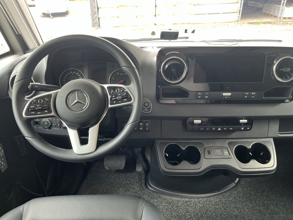 Interiér obytného auta Mercedes s moderním ovládáním a pohodlnými prvky pro řidiče.