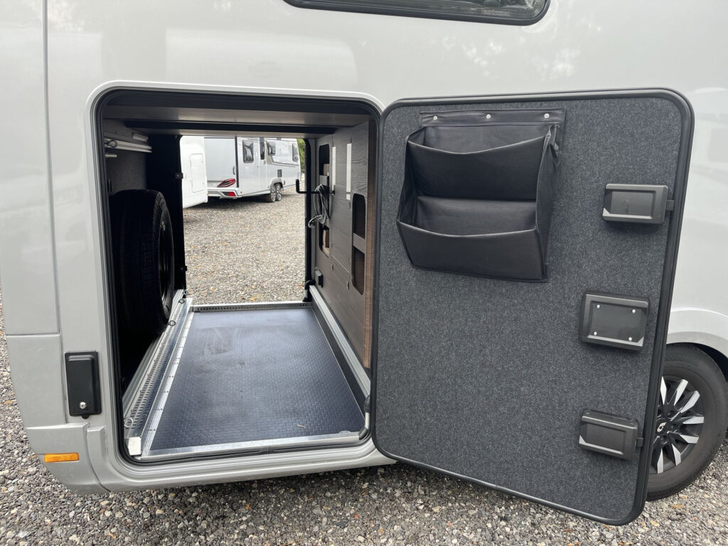 Obrázek zobrazuje úložný prostor obytného auta s tmavou podlahou a zástěrou. Značka a model nejsou viditelné.