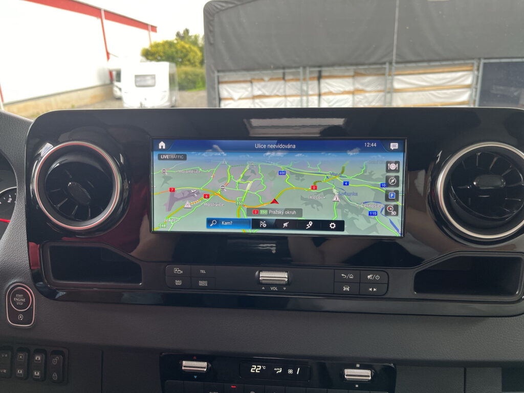 Obrázek ukazuje moderní palubní desku obytného vozu s navigací a ovládacími prvky.