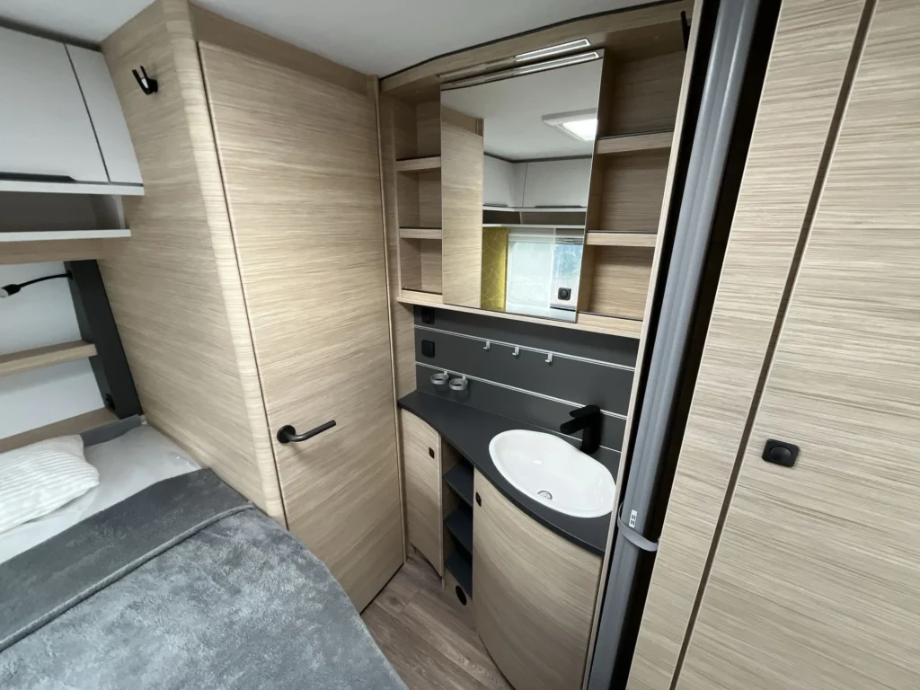 Interiér moderního obytného auta s prostorným úložným prostorem a stylovou koupelnou. Elegantní design a komfort.