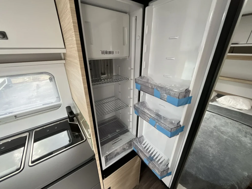 Obrázek ukazuje moderní lednici v karavanu, ideální pro dovolenou na cestách. Vybavení pro pohodlné vaření.