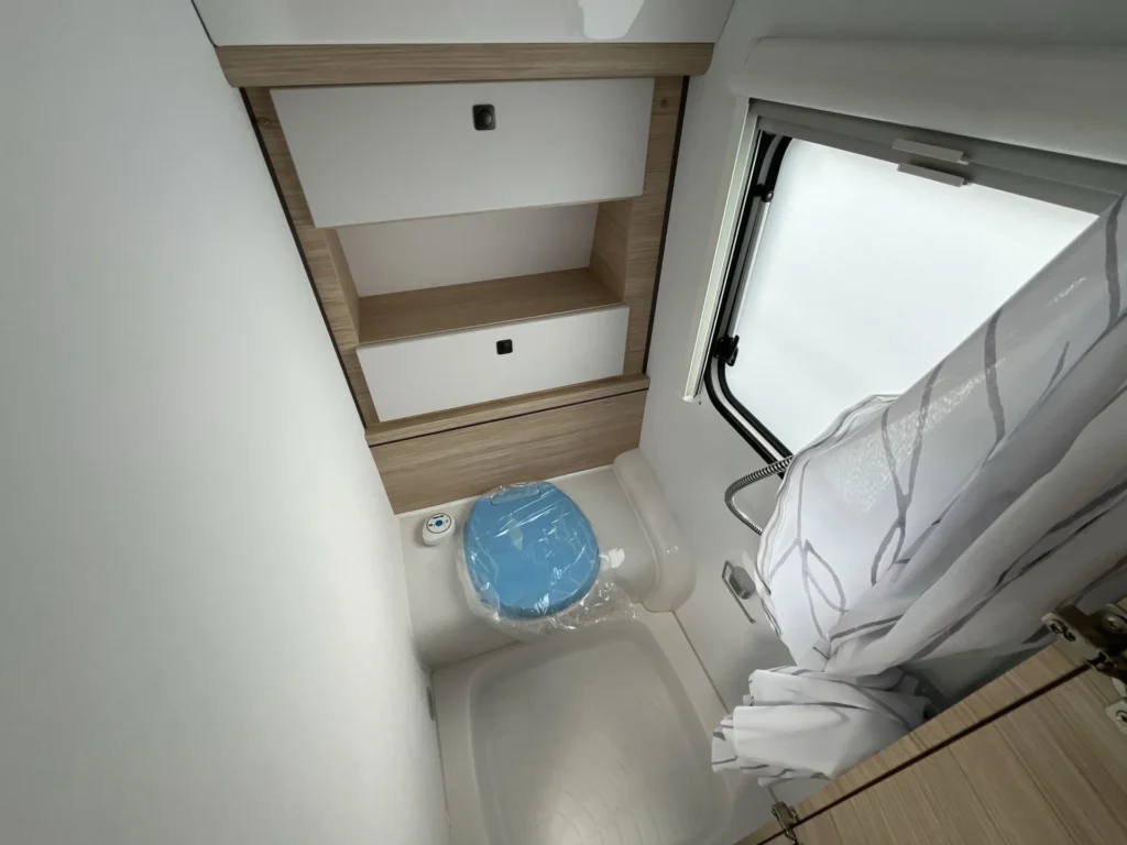 Koupelnový kout s toaletou a úložnými prostory v obytném voze. Moderní design a pohodlí na cestách.