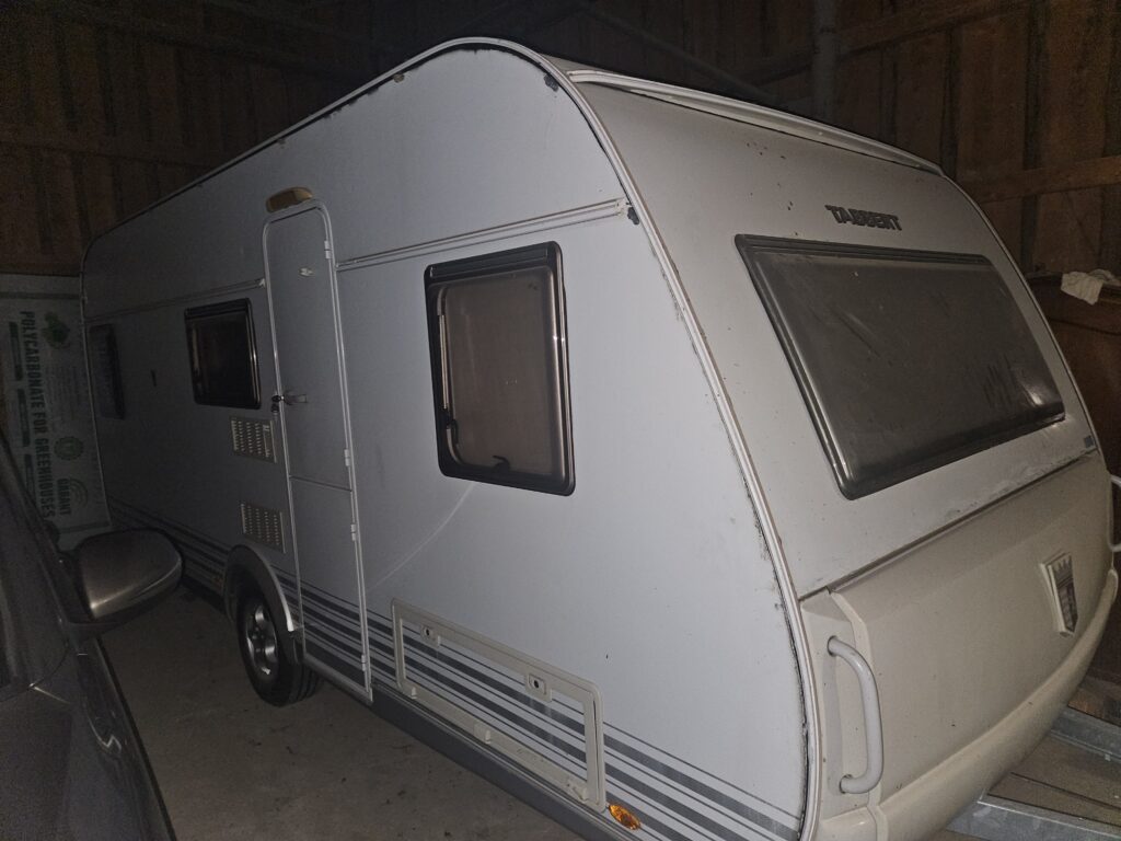 Karavan Tabbert v garáži, zachovalý stav s minimálním poškozením. Ideální pro dobrodružné cesty.