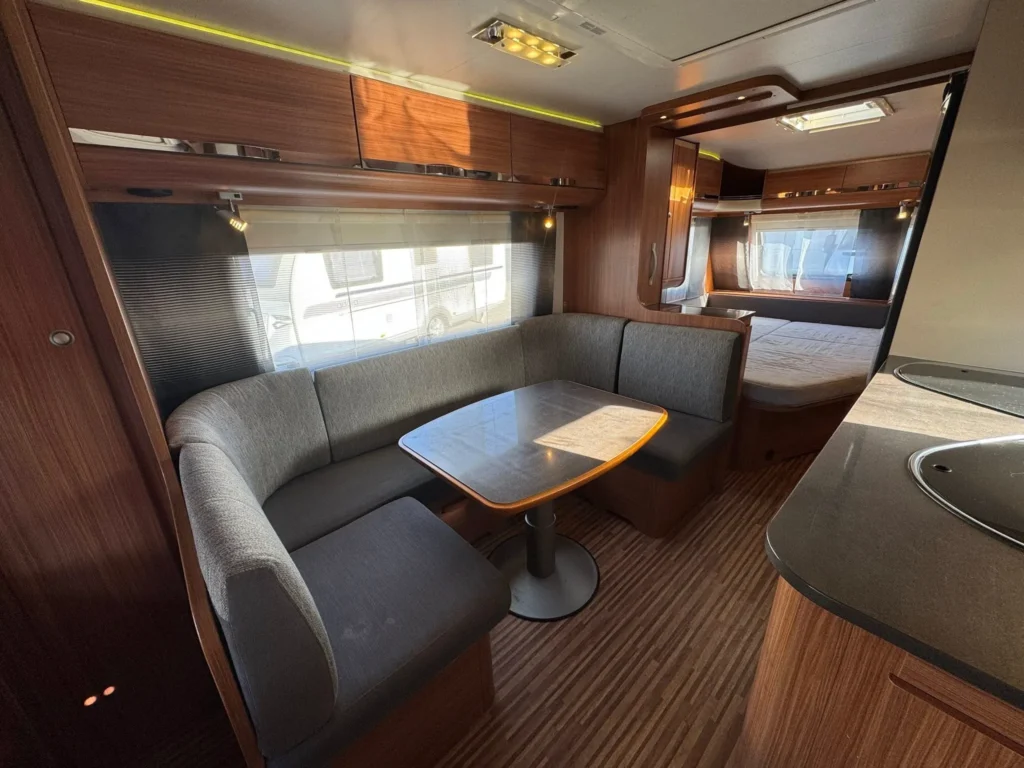 Interiér karavanu s komfortním posezením a kuchyňským koutem. Vhodné pro víkendové výlety.