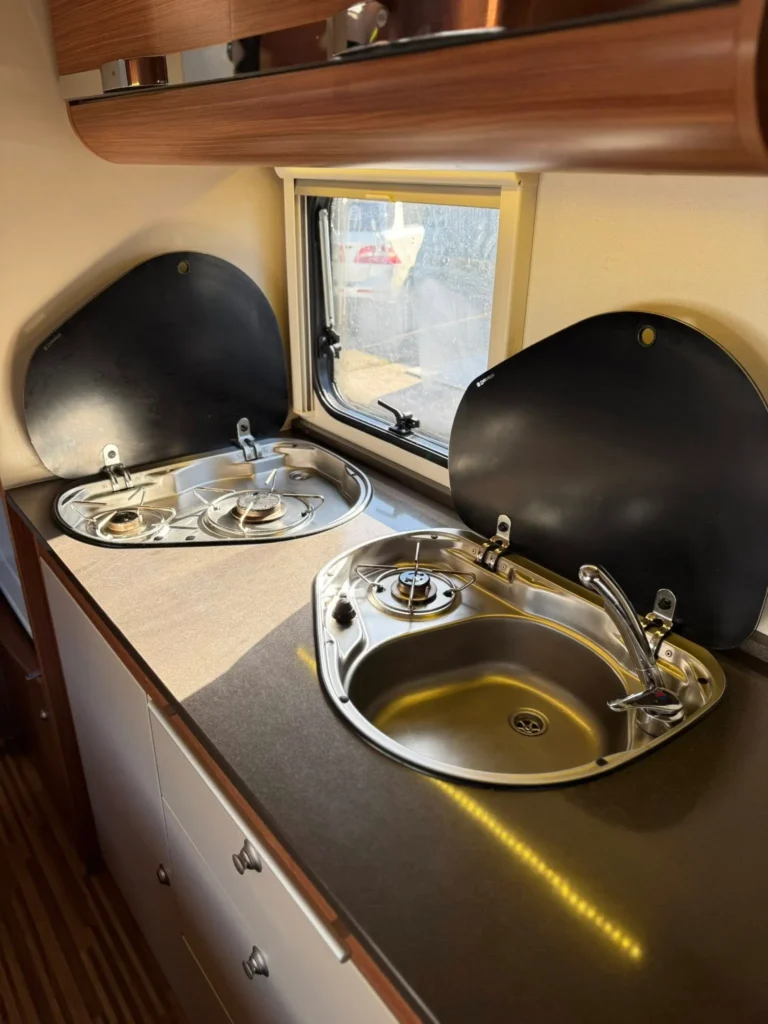 Kuchyňka v karavanu s dvojkombinovaným vařičem a dřezem. Ideální pro vaření na cestách.