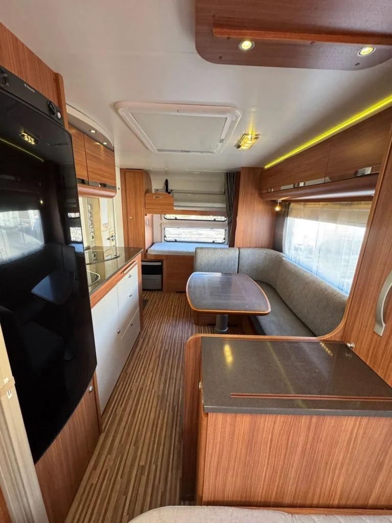 Interiér karavanu s moderním designem a dřevěnými prvky. Prostorný a pohodlný s kuchyňským koutem.