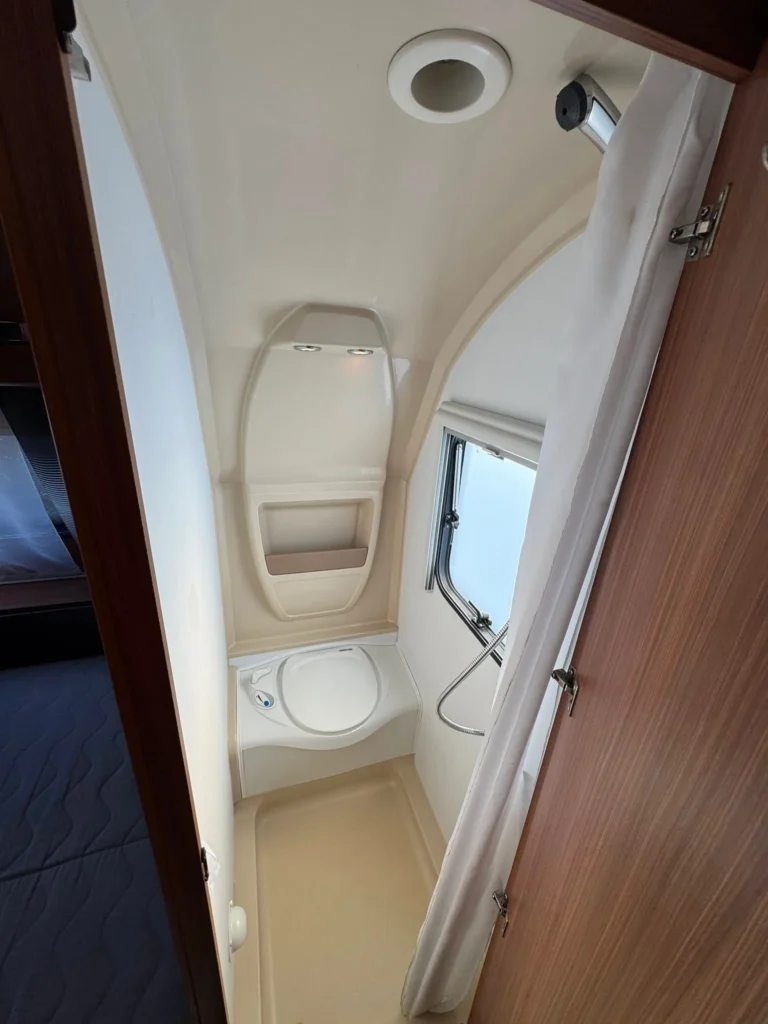 Koupelnový kout v karavanu. Moderní design s umyvadlem a sprchou pro pohodlné cestování.