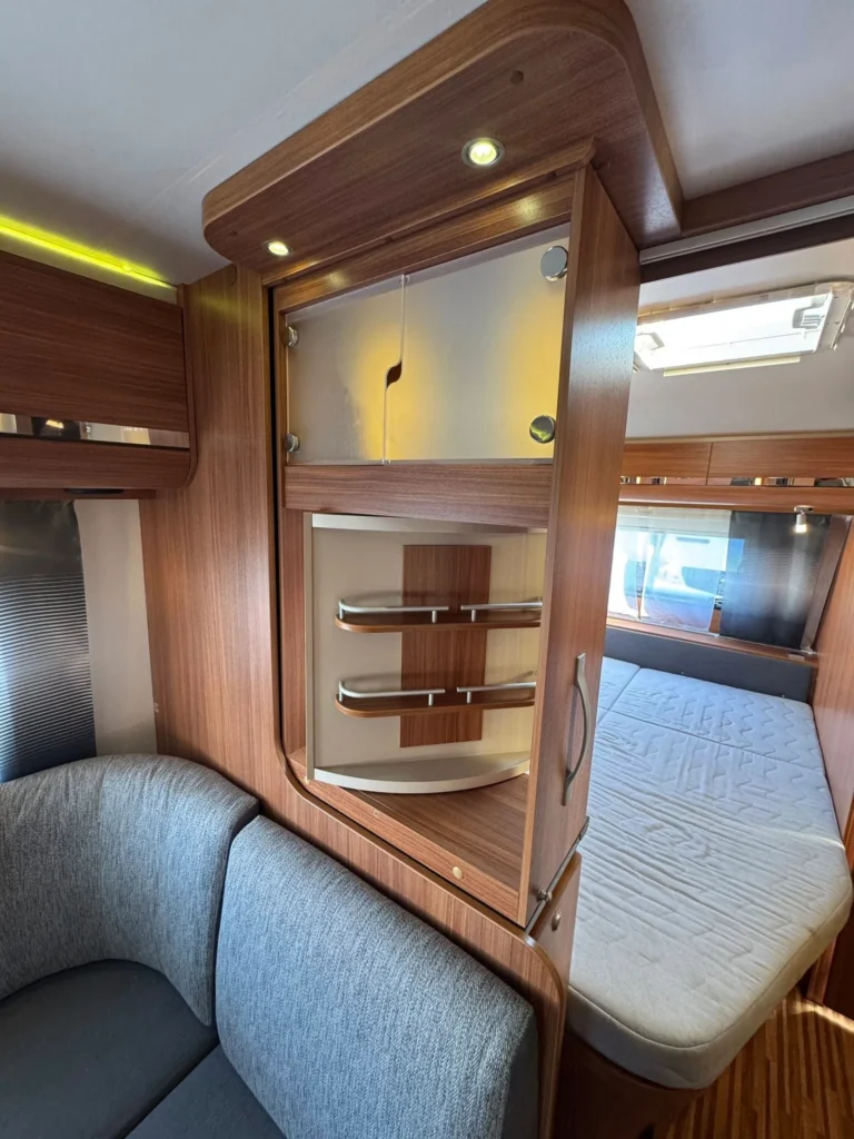 Interiér obytného vozu s moderním nábytkem a pohodlným posezením. Elegantní design a praktické úložné prostory.