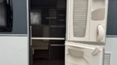 Obrázek zobrazuje vchod do karavanu s moderním designem a praktickými detaily.