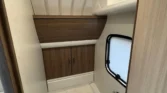 Koupelna v karavanu s toaletou, skříňkami a oknem. Moderní design pro pohodlí při cestování.