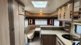 Obrázek interiéru karavanu s moderním designem, dřevěnými prvky a kuchyňským koutem. Ideální pro pohodlné cestování.