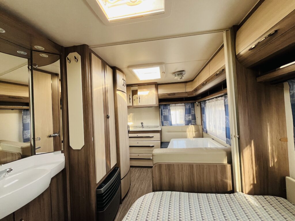 Interiér karavanu s dřevěnými obklady a prostorným uspořádáním. Ideální pro pohodlné cestování a odpočinek.