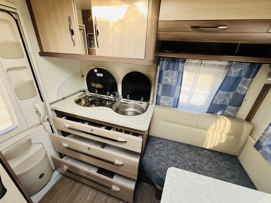 Interiér karavanu s kuchyňkou a pohodlným posezením. Ideální pro cesty a dobrodružství.