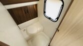 Obrázek zobrazuje koupelnu v karavanu, moderní design s toaletou a skříňkami pro úložný prostor.