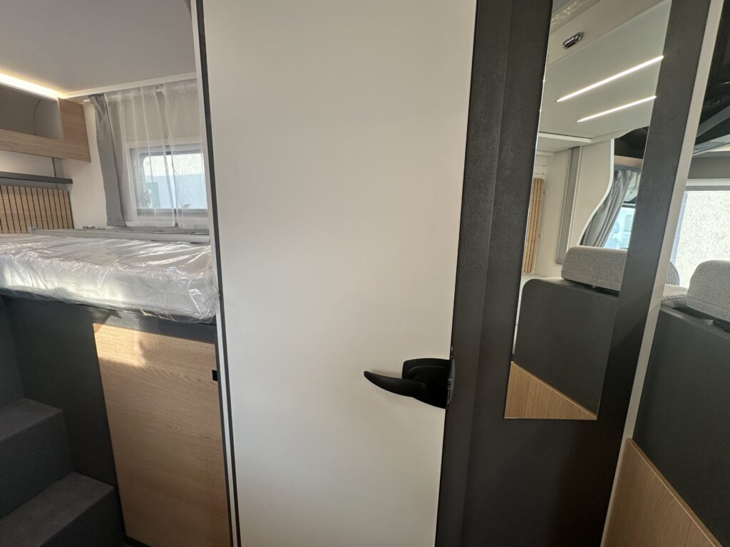 Obrázek interiéru karavanu s elegantním designem a prostorem pro spaní. S vámi na cestách komfortně!