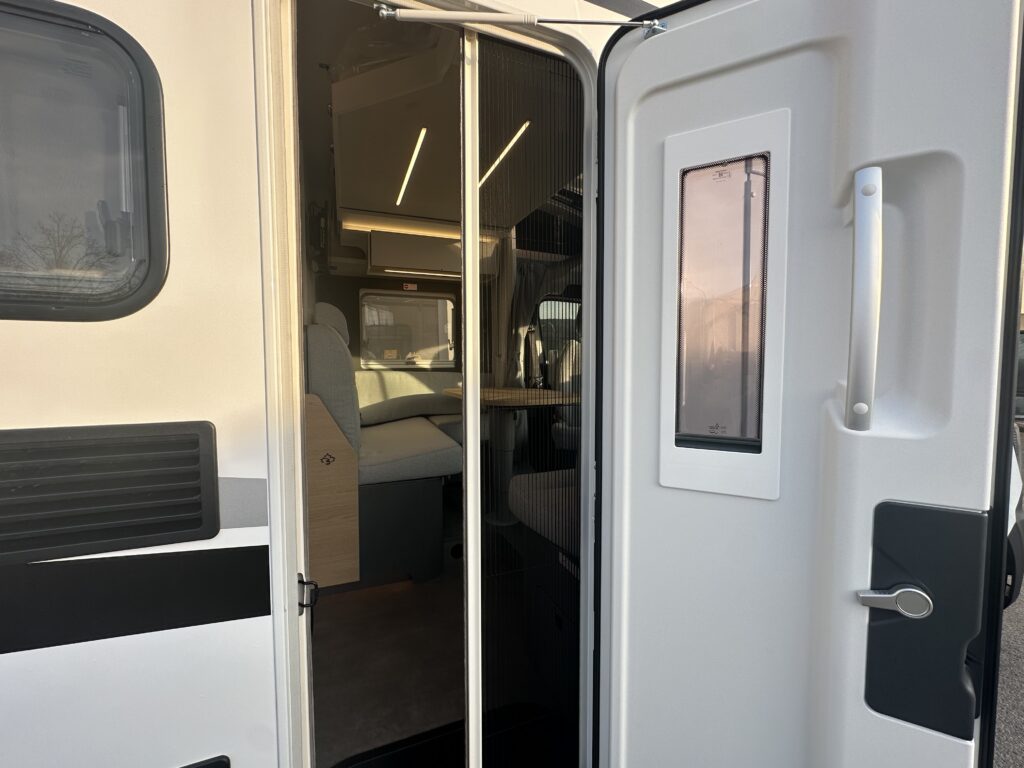 Obrázek zobrazuje vstup do obytného auta, moderního a prostorného interiéru.