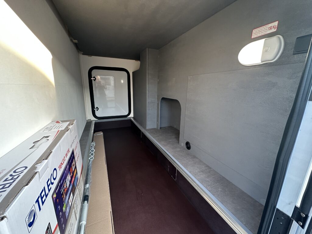 Interiér obytného vozu s prostorem pro úložné vybavení a osvětlením. Detailní zpracování a moderní design.