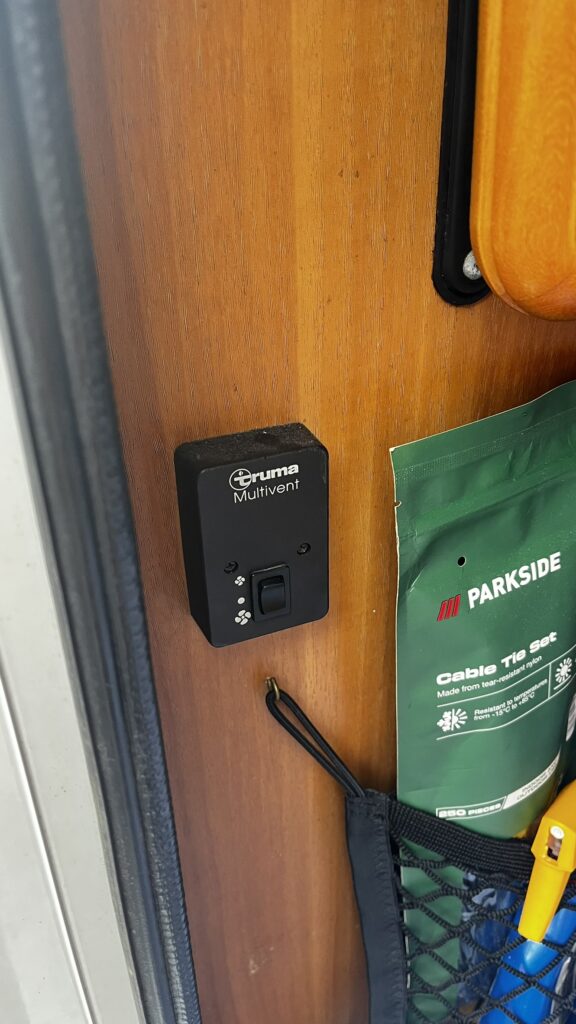 Na obrázku je ovládací panel Truma Multivent v interiéru obytného vozu. Ideální pro pohodlné užívání.