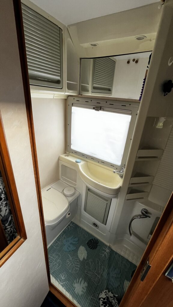 Koupelna v obytném voze s moderním vybavením. Umyvadlo, toaleta a sprchový kout. Komfort na cestách.