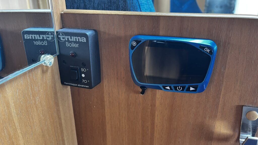 Obrázek z interiéru obytného vozu s ovládáním boileru Truma a displejem. Ideální pro pohodlné cestování.