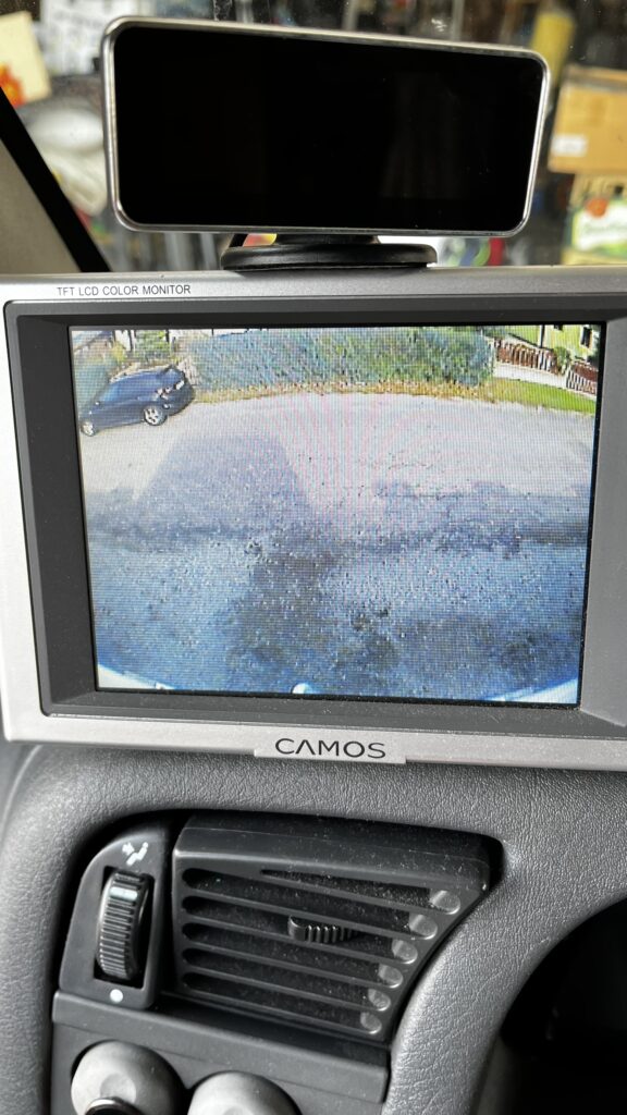 Obrázek z monitoru ukazuje parkování obytného auta. Značka a model nejsou viditelné.