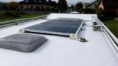 Obrázek zobrazuje střechu obytného auta s solárním panelem a střešními okny. Ideální pro kempování!