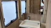Obrázek interiéru karavanu s koupelnou a sprchovým koutem, moderní design a funkční prvky.
