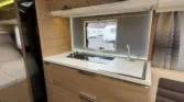 Interiér obytného auta s moderní kuchyňkou a komfortním posezením. Vybavení z kvalitního dřeva pro pohodlné cestování.
