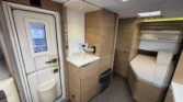 Interiér moderního obytného auta s kuchyňkou a úložným prostorem. Elegantní design a funkční uspořádání.