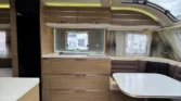 Interiér karavanu s moderním designem, kuchyňka a posezení pro pohodlné bydlení na cestách.