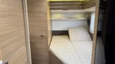 Interiér moderního karavanu s pohodlnými postelemi a dřevěnými obklady. Ideal pro relaxaci na cestách.