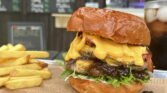 Obrázek ukazuje burger s chedarem a hranolky, ideální pro milovníky dobrého jídla.